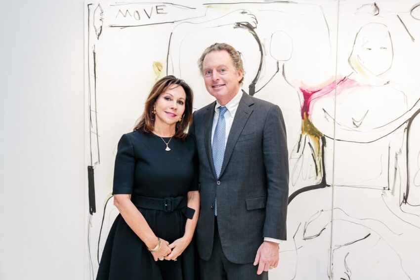 A man and a woman dressed formally standing in front of an abstract painting.