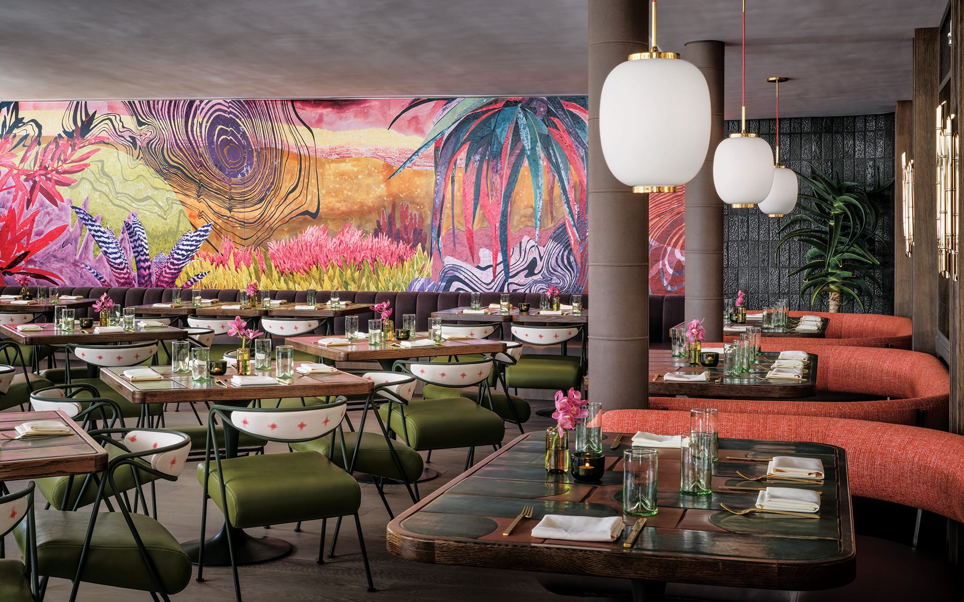 Colorful restaurant interior with vibrant mural, elegant lighting, and neatly set tables, evoking a lively and inviting atmosphere.