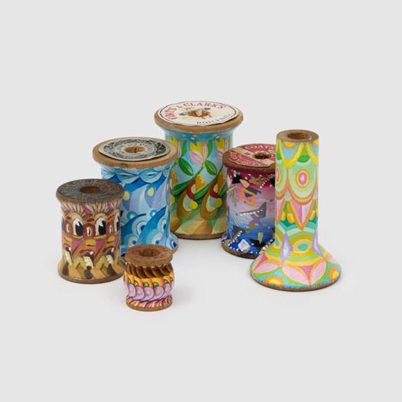 Colorful painted wooden spools in various sizes arranged together on a plain background.