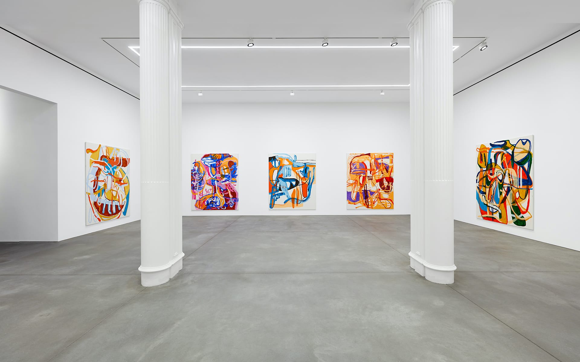 Art gallery interior with five colorful abstract paintings on white walls, featuring two central white columns.