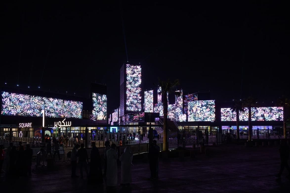 Colorful illuminated buildings at night in Riyadh Season 2023, with people gathered in the foreground.