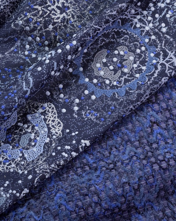 Close-up of blue lace fabric with intricate circular and dotted patterns.