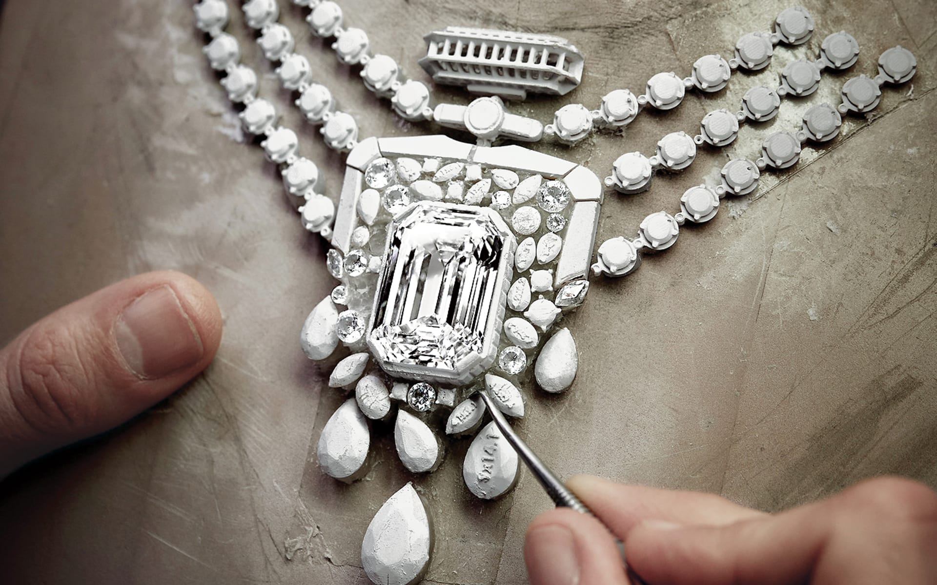 Craftsman working on intricate diamond necklace with detailed gemstones and elegant design elements.