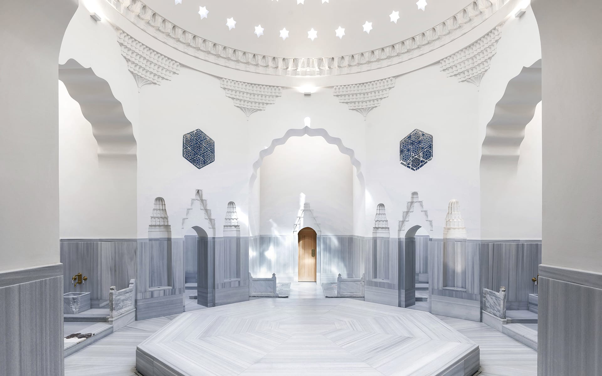 Interior of a traditional Turkish bath with ornate dome ceiling and marble fixtures.