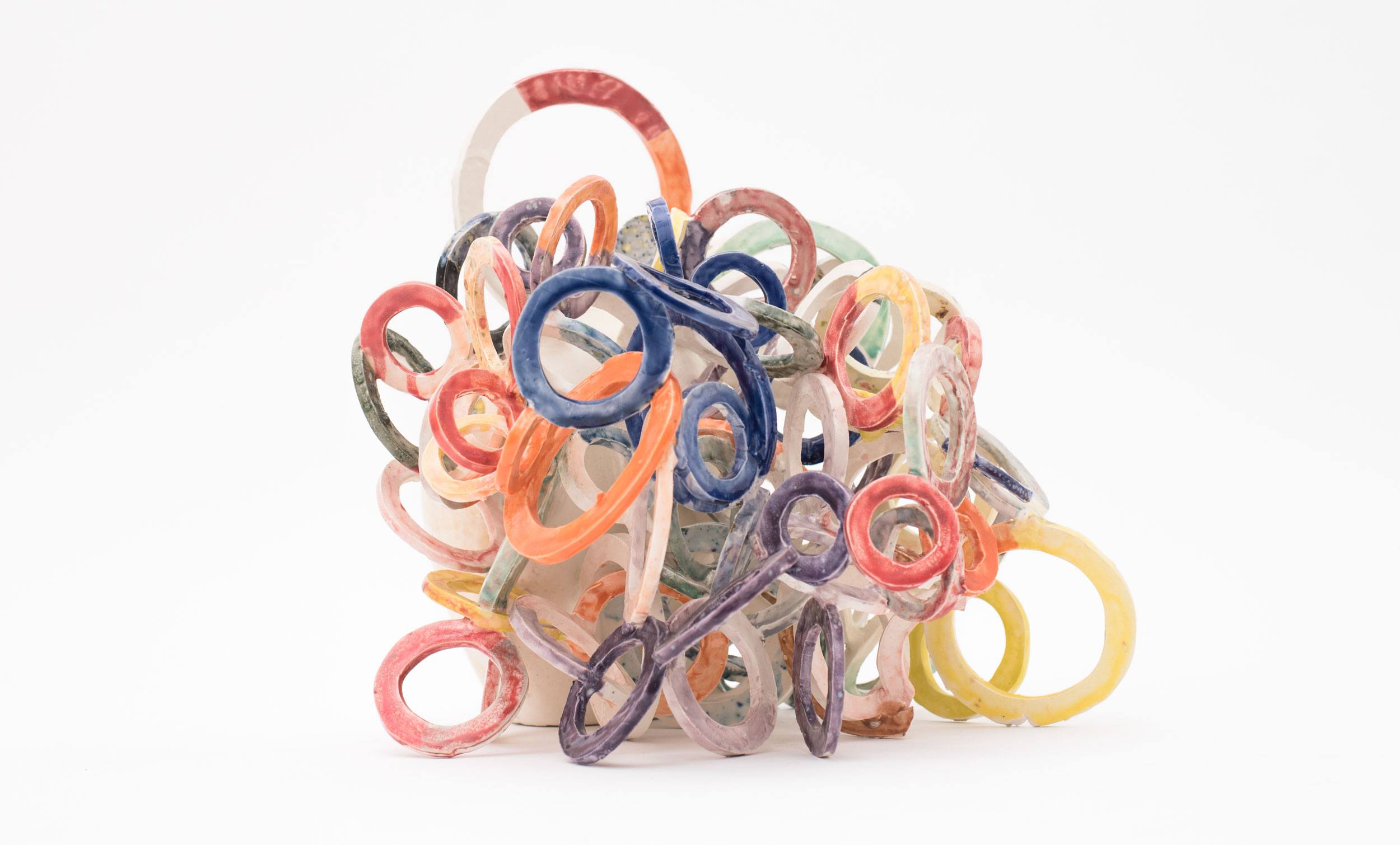 Colorful plastic loops tangled in a pile on a white background.