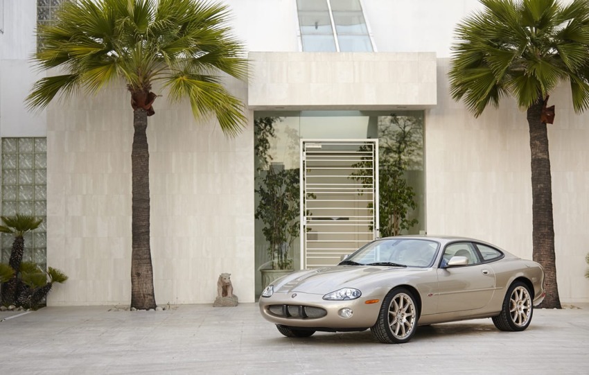 Silver sports car parked in front of a modern white building with palm trees.