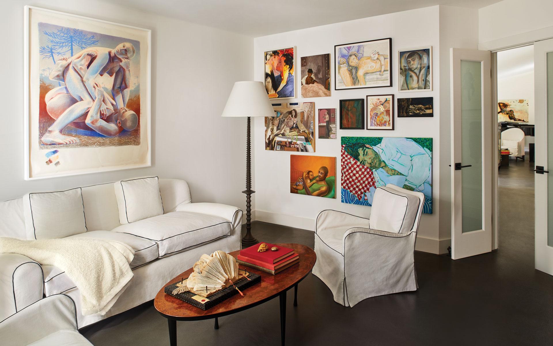 Living room with white furniture, eclectic wall art display, and a cozy atmosphere.