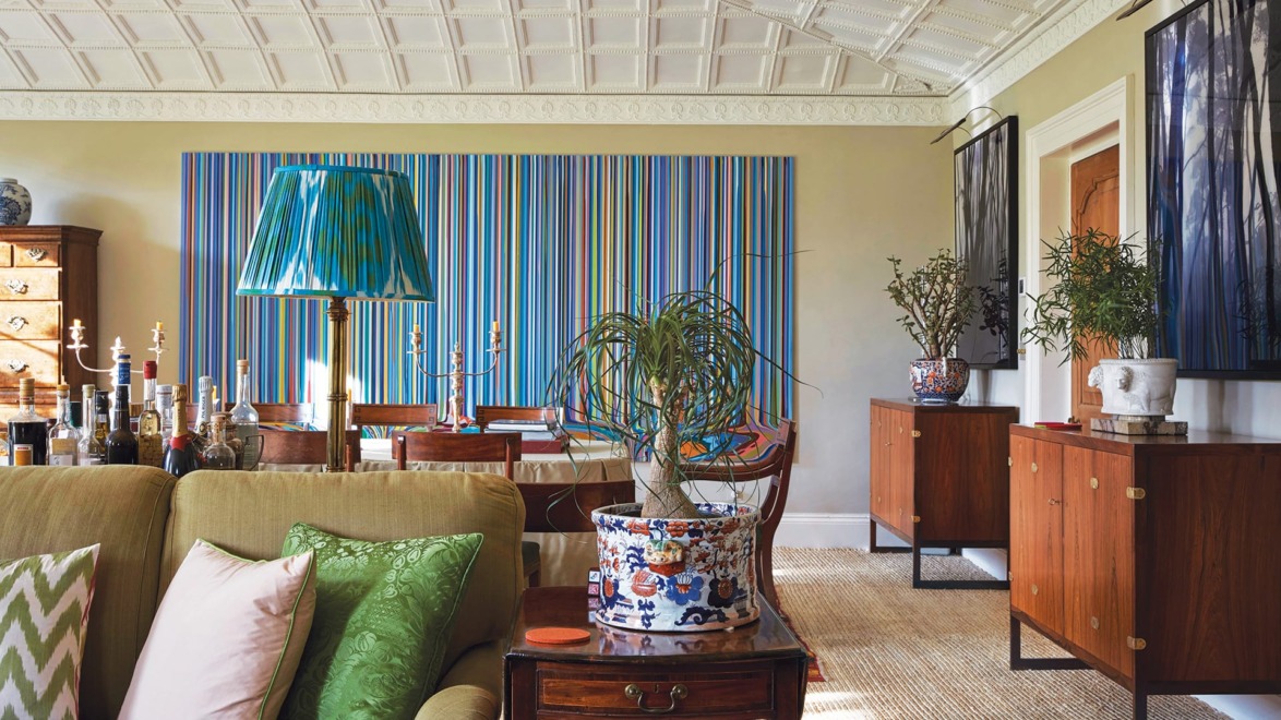 Stylish living room with patterned ceiling, colorful striped wall art, cozy seating, and elegant decorative elements.