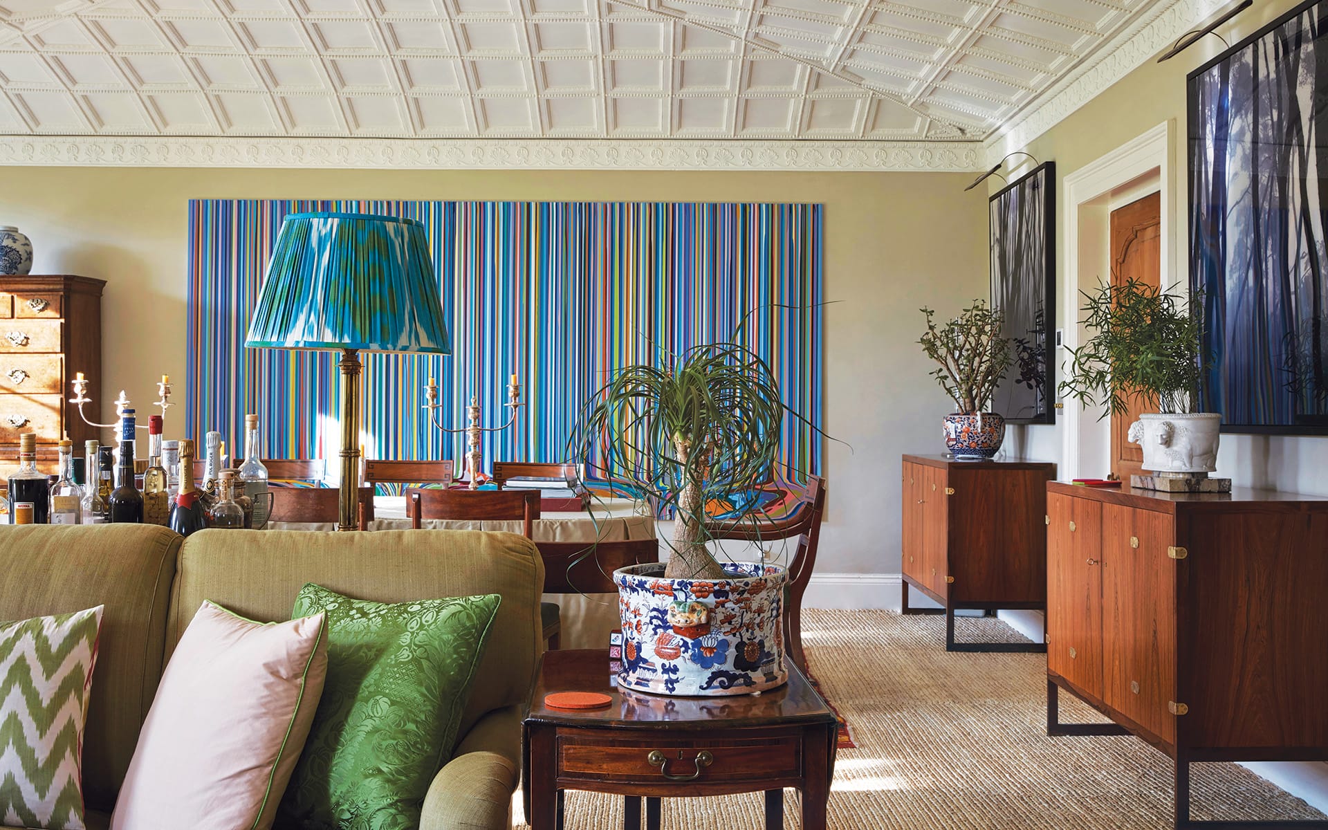 Stylish living room with patterned ceiling, colorful striped wall art, cozy seating, and elegant decorative elements.