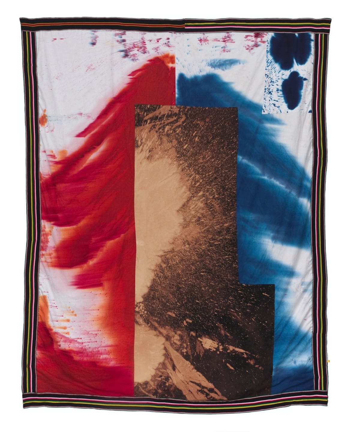 Abstract fabric artwork with bold red, blue, and brown patterns on a bordered textile background