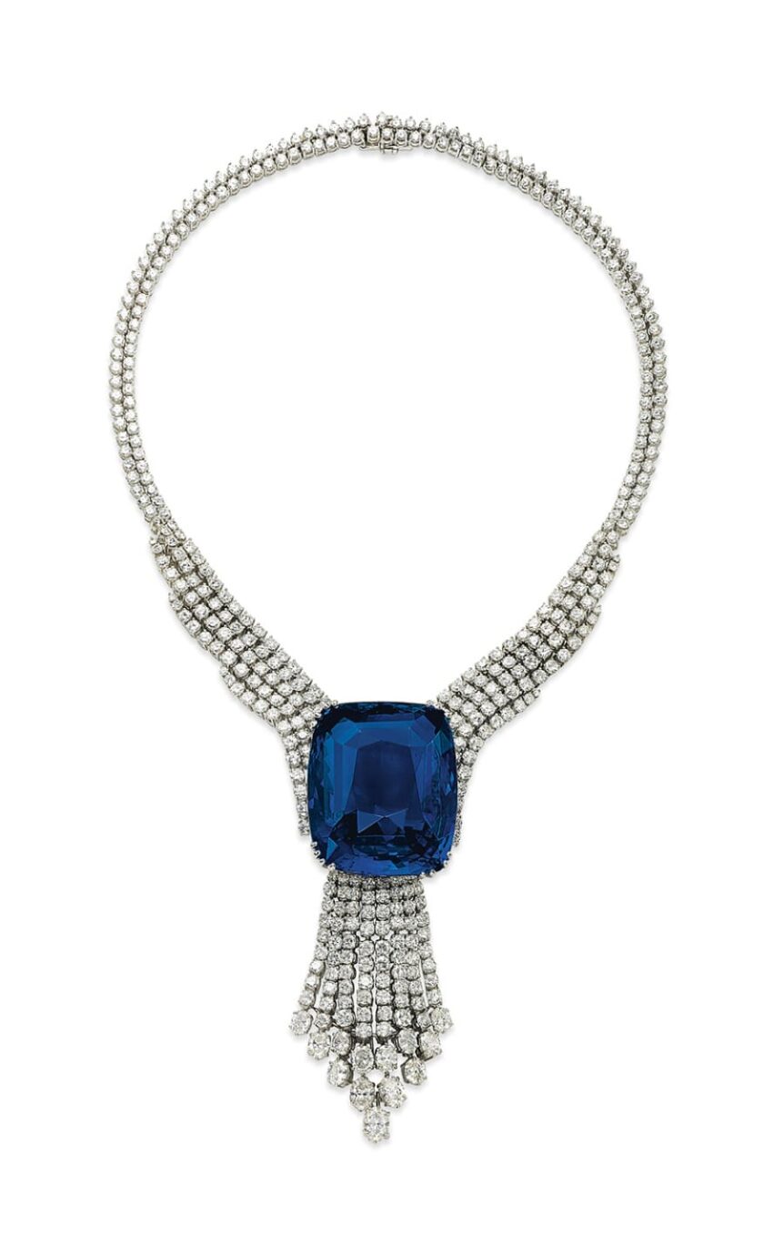 Elegant necklace with a large blue gemstone and cascading diamond accents on a silver chain.