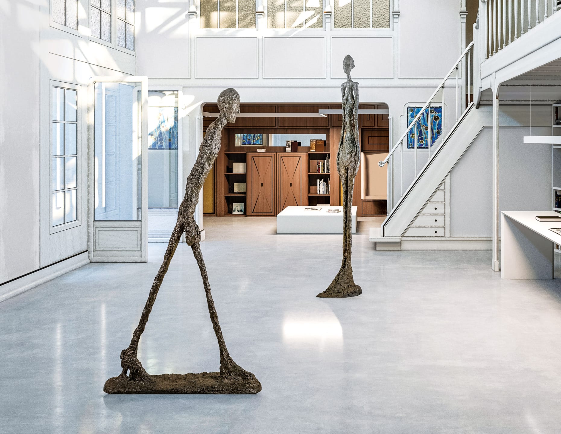 Two tall, slender sculptures in an airy, modern gallery space with large windows and bright lighting.