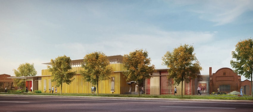 Modern building facade with yellow panels, surrounded by trees and people walking on a sunny day.