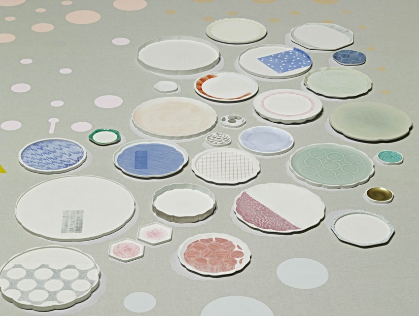 Assorted colorful ceramic plates arranged artistically on a light green surface with circular patterns.