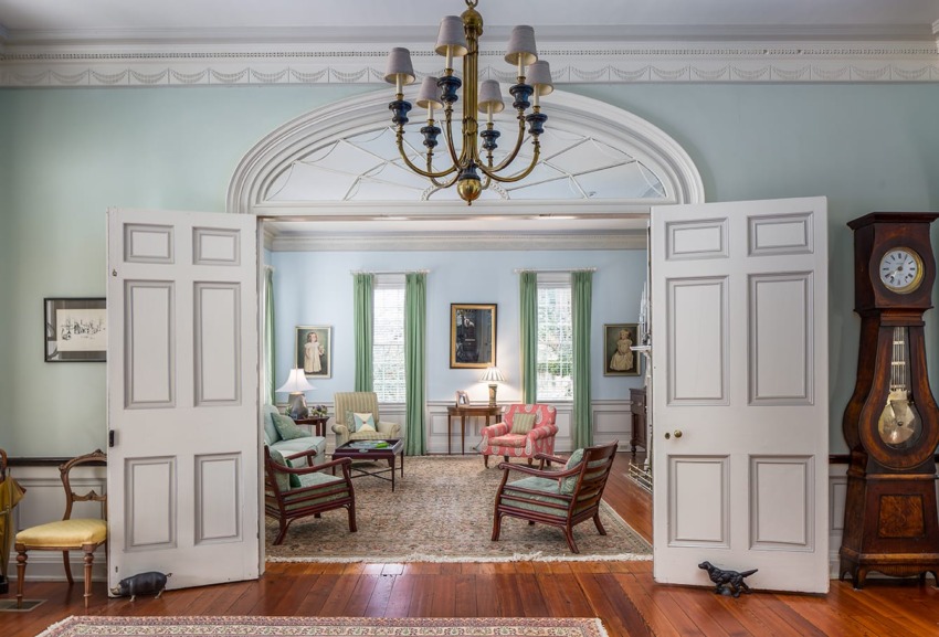 Elegant living room with light blue walls, classic furniture, chandelier, and vintage clock.