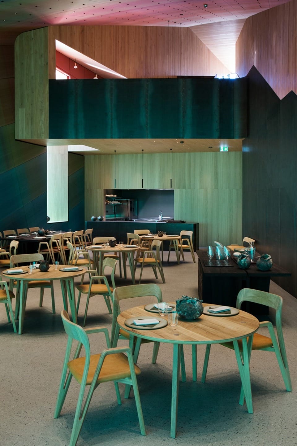 Contemporary restaurant interior with wooden furniture, round tables, and stylish lighting.