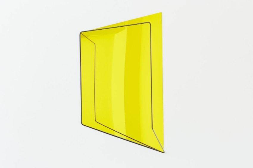 Yellow geometric abstract shape with sharp angles and lines against a plain white background.