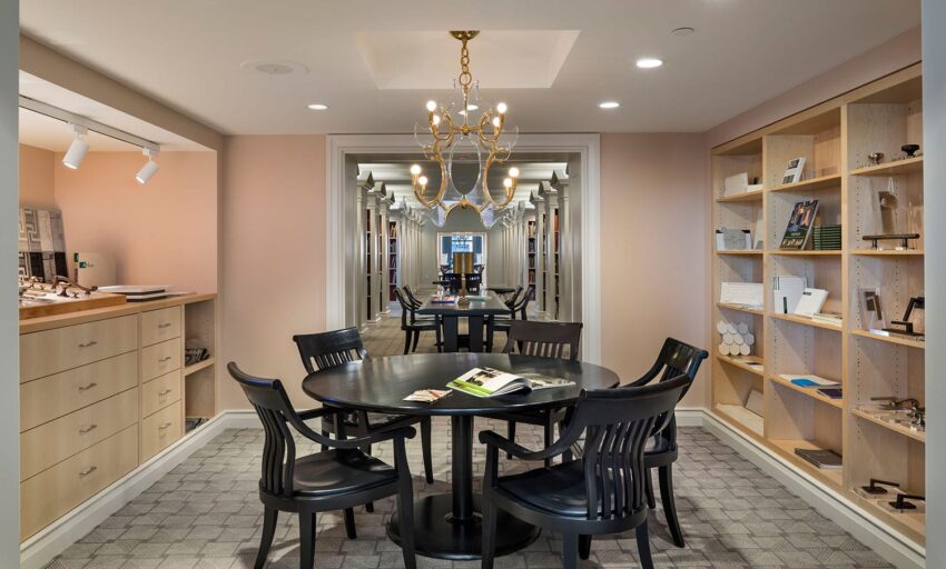 Luxurious interior meeting room with a round table, elegant chandelier, display shelves, and a mirrored wall.