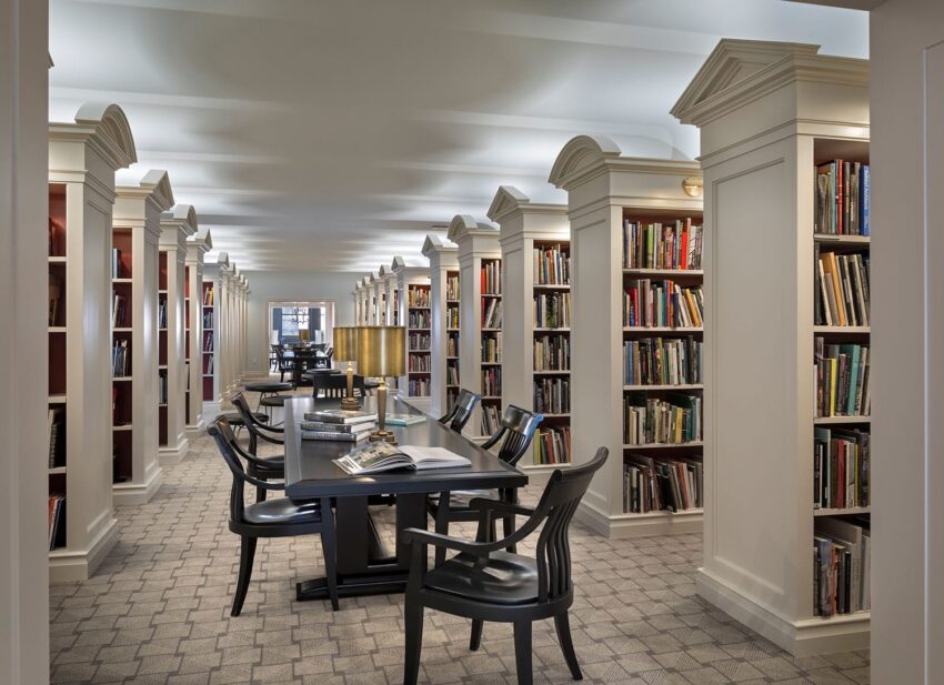 Modern library interior with rows of bookshelves and tables, illuminated by soft lighting, creating a cozy reading environment.