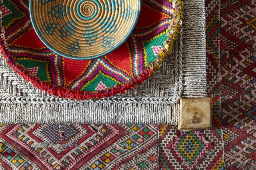 Colorful woven baskets and rugs with intricate geometric patterns displayed in a vibrant arrangement.