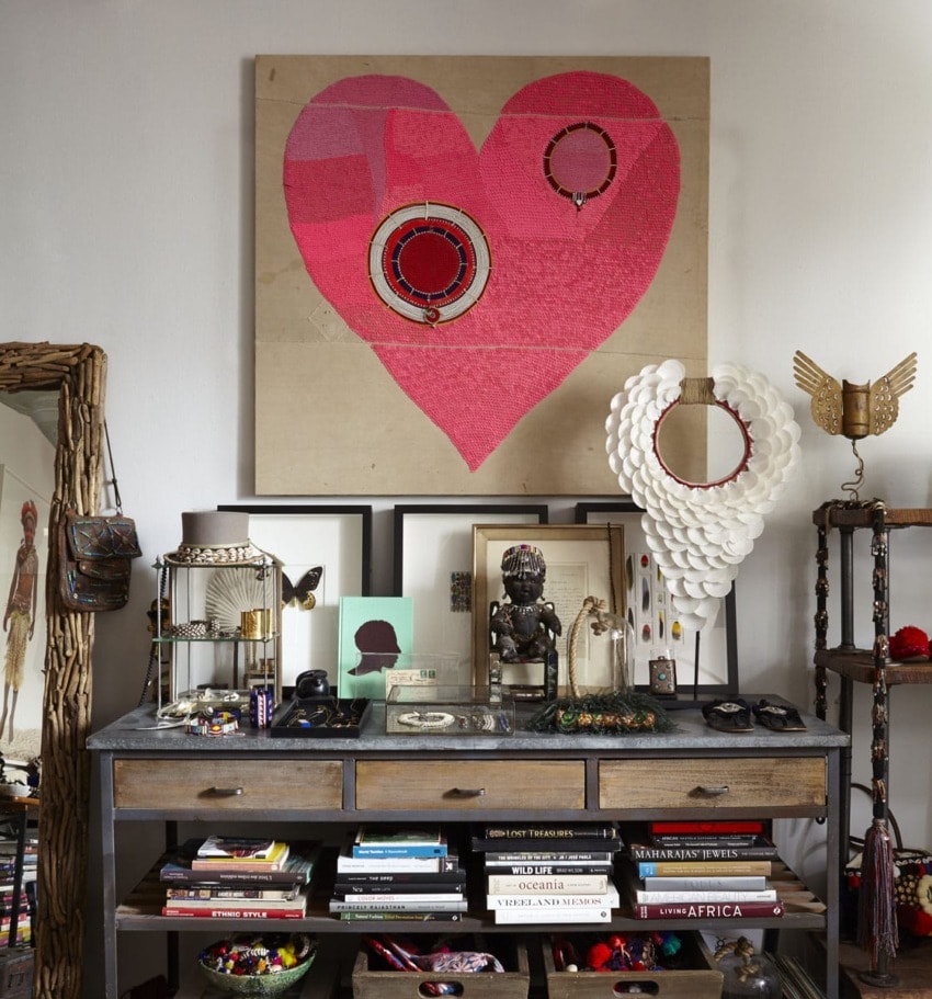 Eclectic room with heart artwork, books, and decorative items on a wooden shelf.
