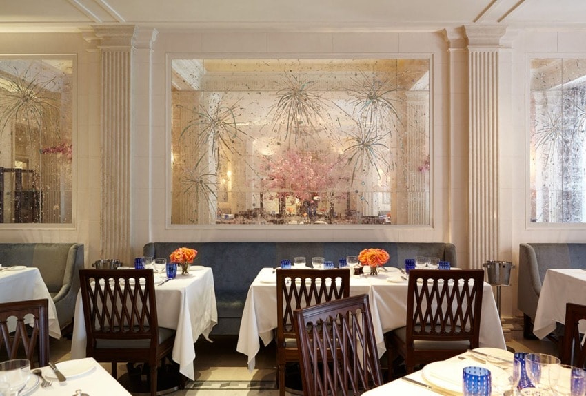 Elegant restaurant interior with neatly arranged tables, blue and orange accents, and decorative glass paneling.