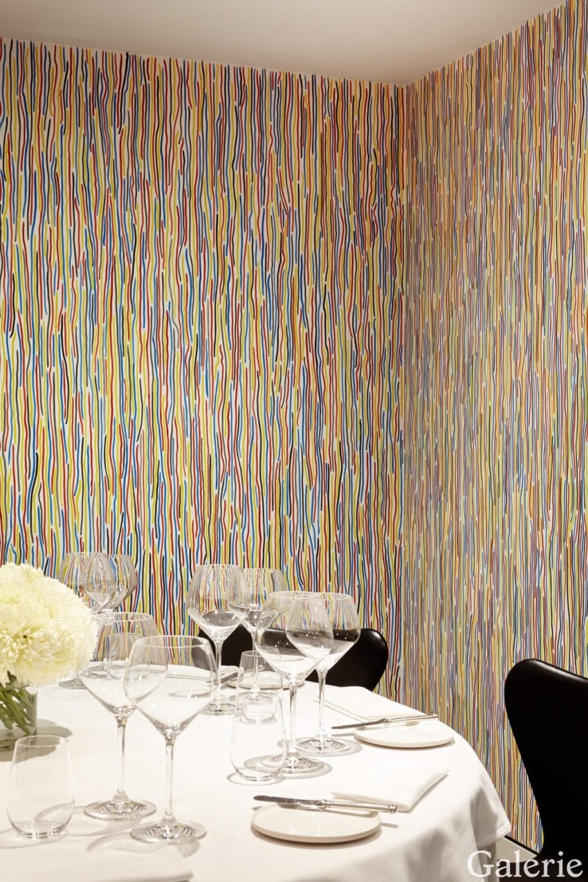 Dining room with colorful striped wallpaper, set table with wine glasses, white tablecloth, and a flower arrangement.