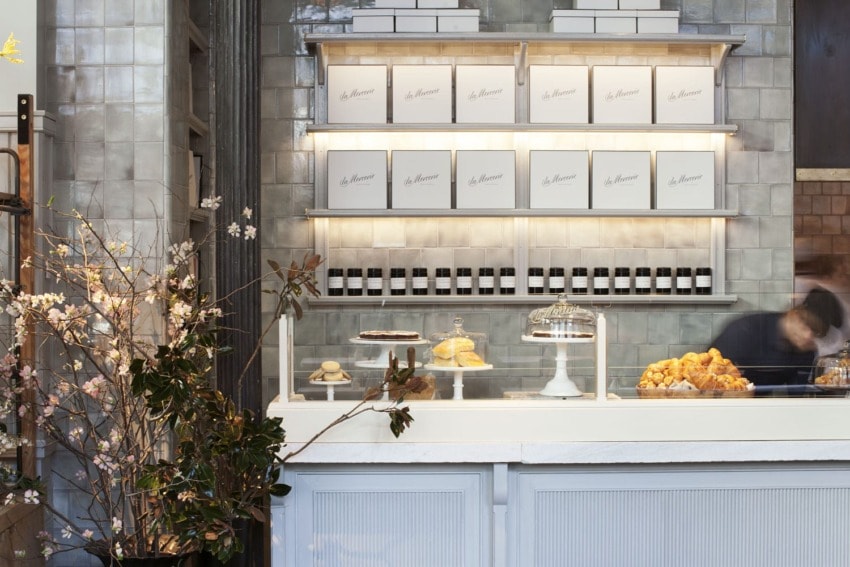 Bakery counter displaying pastries and boxed products with a blurred person in motion behind the counter in a modern interior.