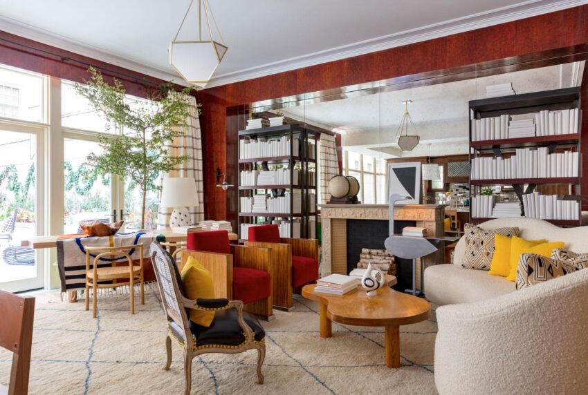 Modern living room with mix of red and white seating, wooden furniture, bookshelves, large windows, and decorative accents.