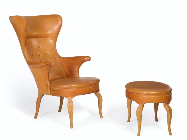 High-backed brown leather chair with a matching round ottoman on elegantly curved wooden legs.
