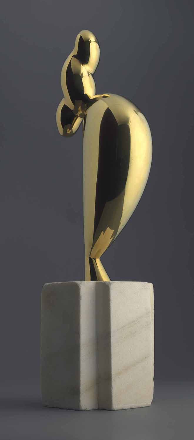 Abstract golden sculpture on a marble base against a gray background.