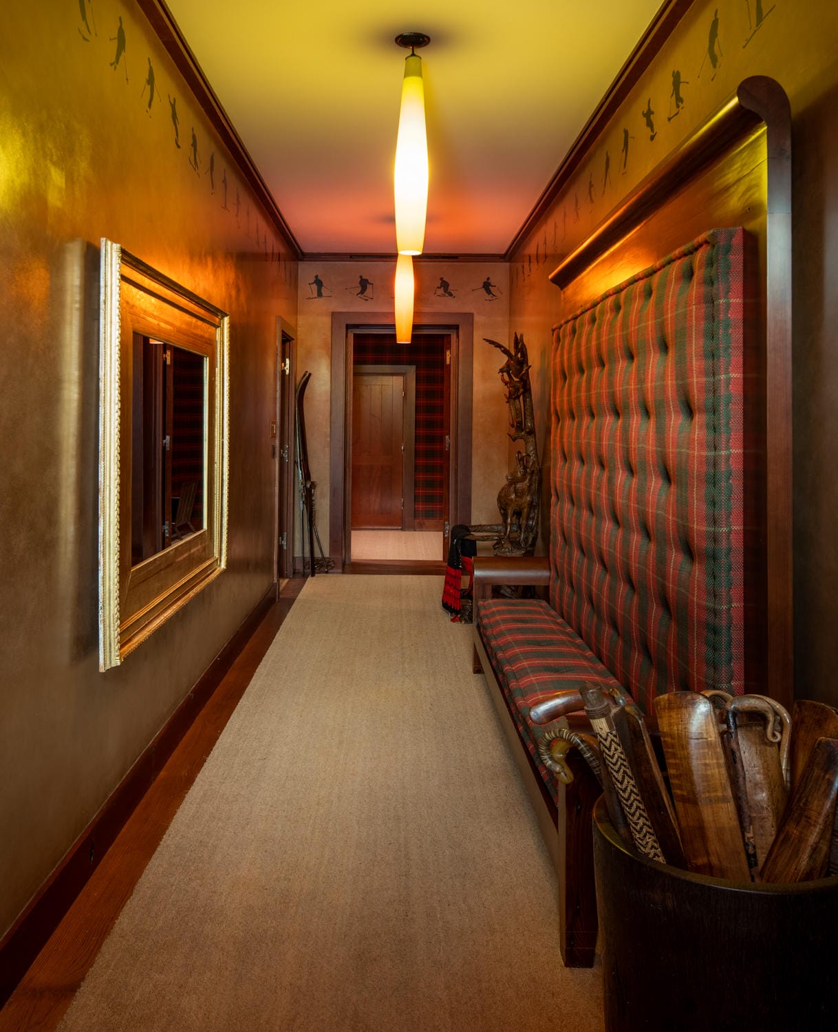 Cozy hallway with plaid seating, large mirror, and warm lighting, showcasing rustic decor elements and wooden accents.