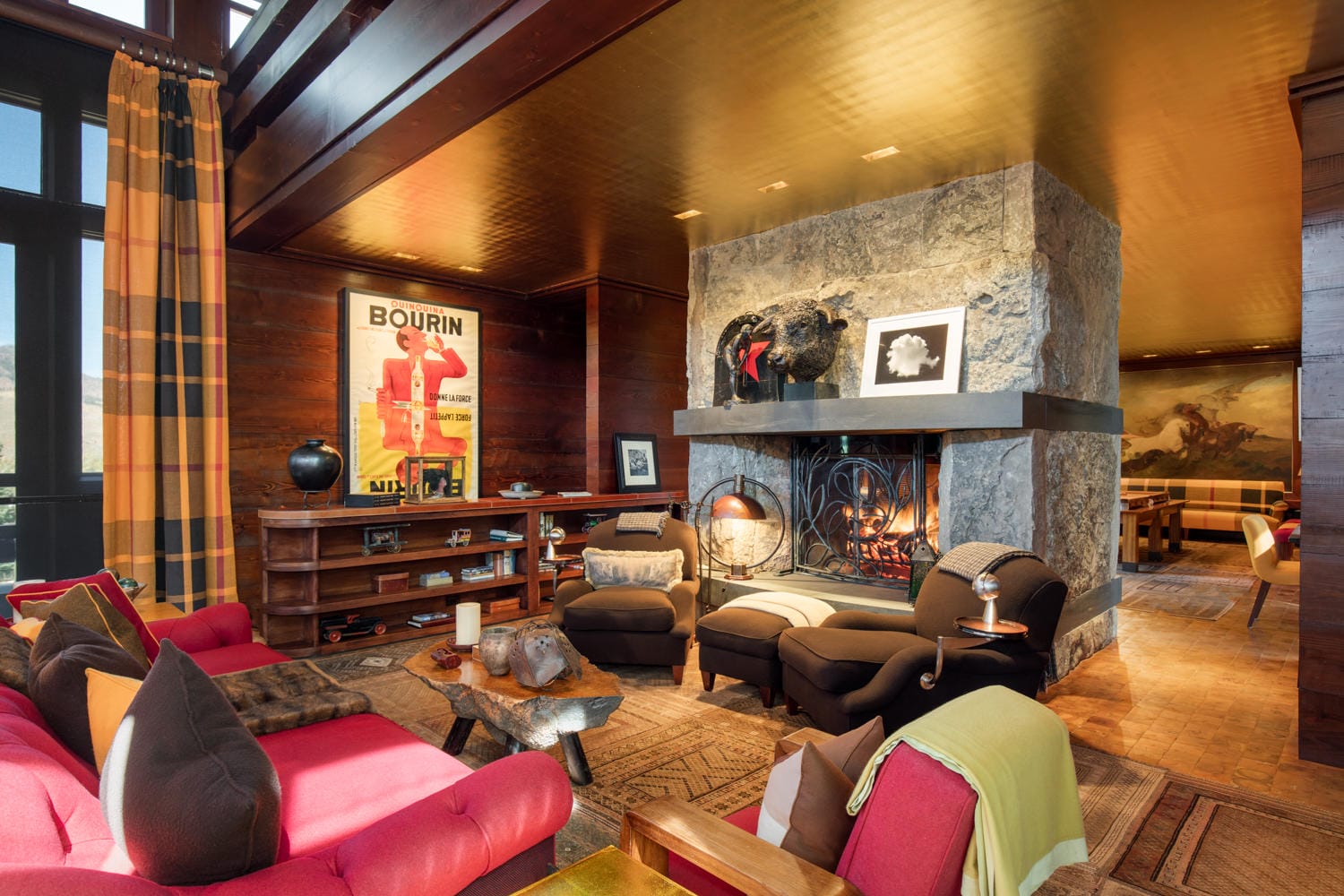 Cozy living room with a stone fireplace, colorful furniture, artwork on the walls, and warm lighting.