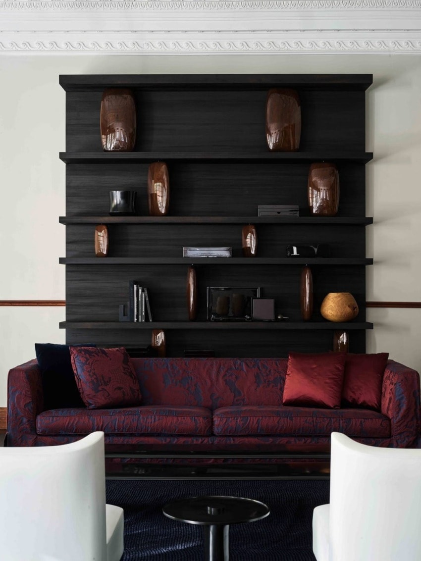 Modern living room with dark shelves, decorative vases, and a burgundy patterned sofa.