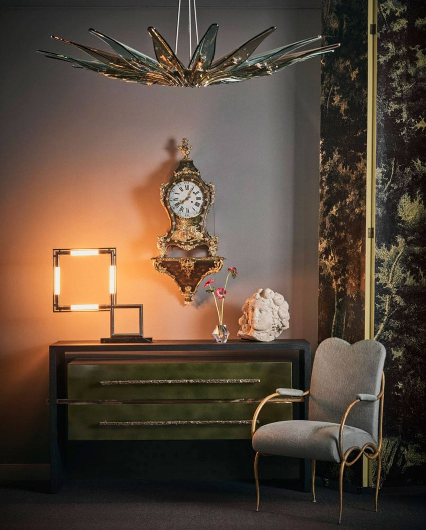 Elegant living room with vintage clock, modern lamp, decorative dresser, soft chair, and a unique star-shaped ceiling light.