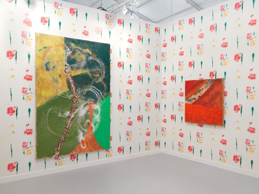 Abstract paintings in a gallery with colorful floral wallpaper covering the walls.