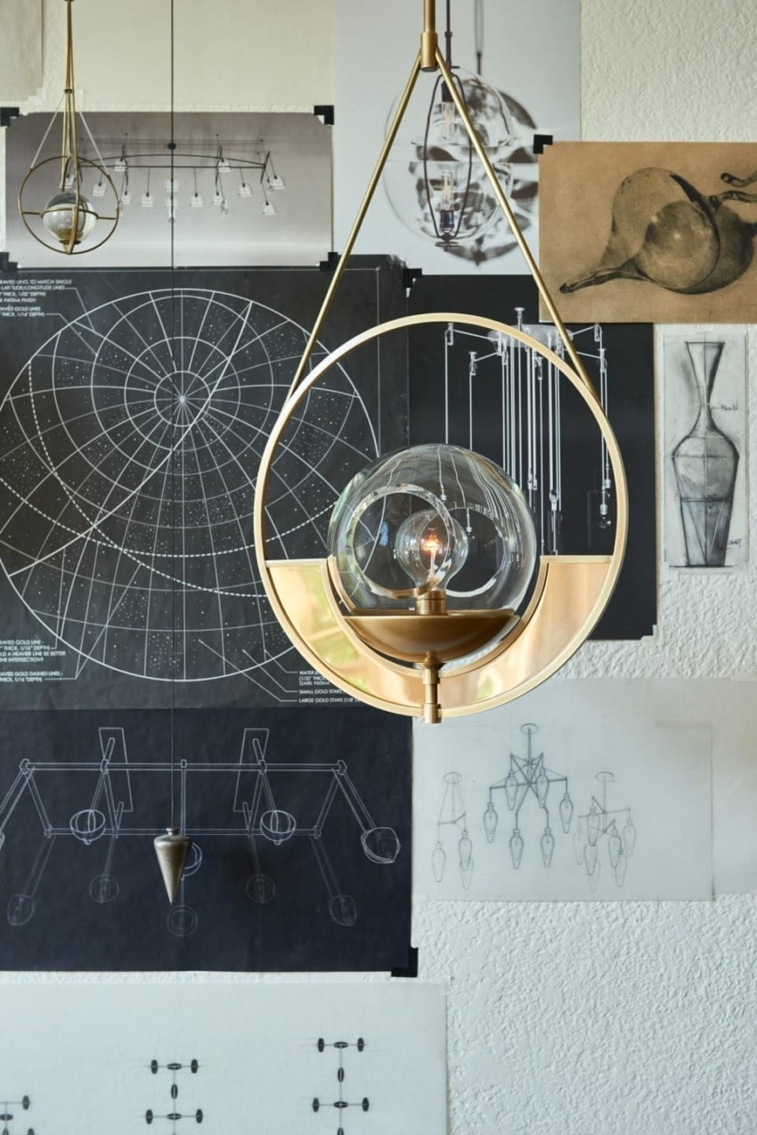 Modern chandelier design with sketches and diagrams displayed on a wall background.