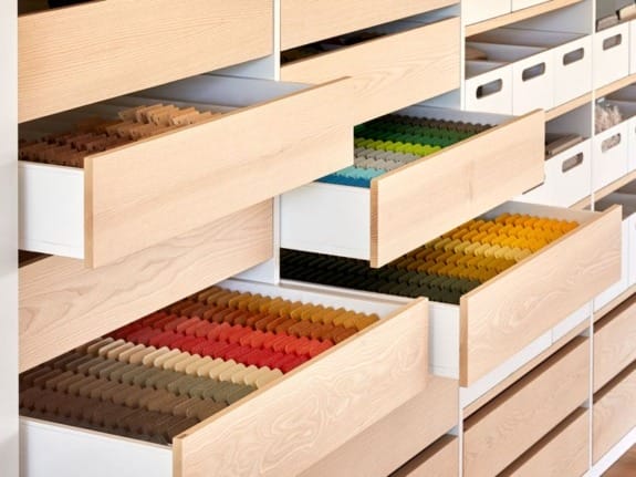 Drawers filled with colorfully organized spools of thread in a neatly arranged storage cabinet.
