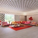 Modern living room with colorful sofas, red rug, geometric ceiling, and large windows showcasing a garden view.