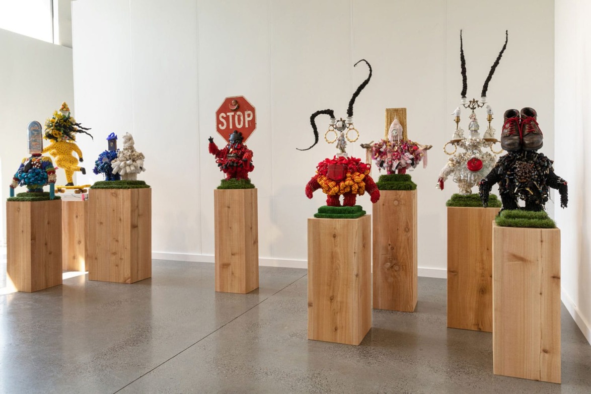 Colorful sculptures on wooden pedestals in a gallery setting with a mix of abstract and surreal elements.