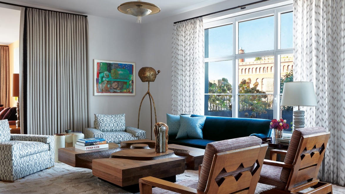 Modern living room with large windows, contemporary furniture, artwork on the wall, and decorative lamp.
