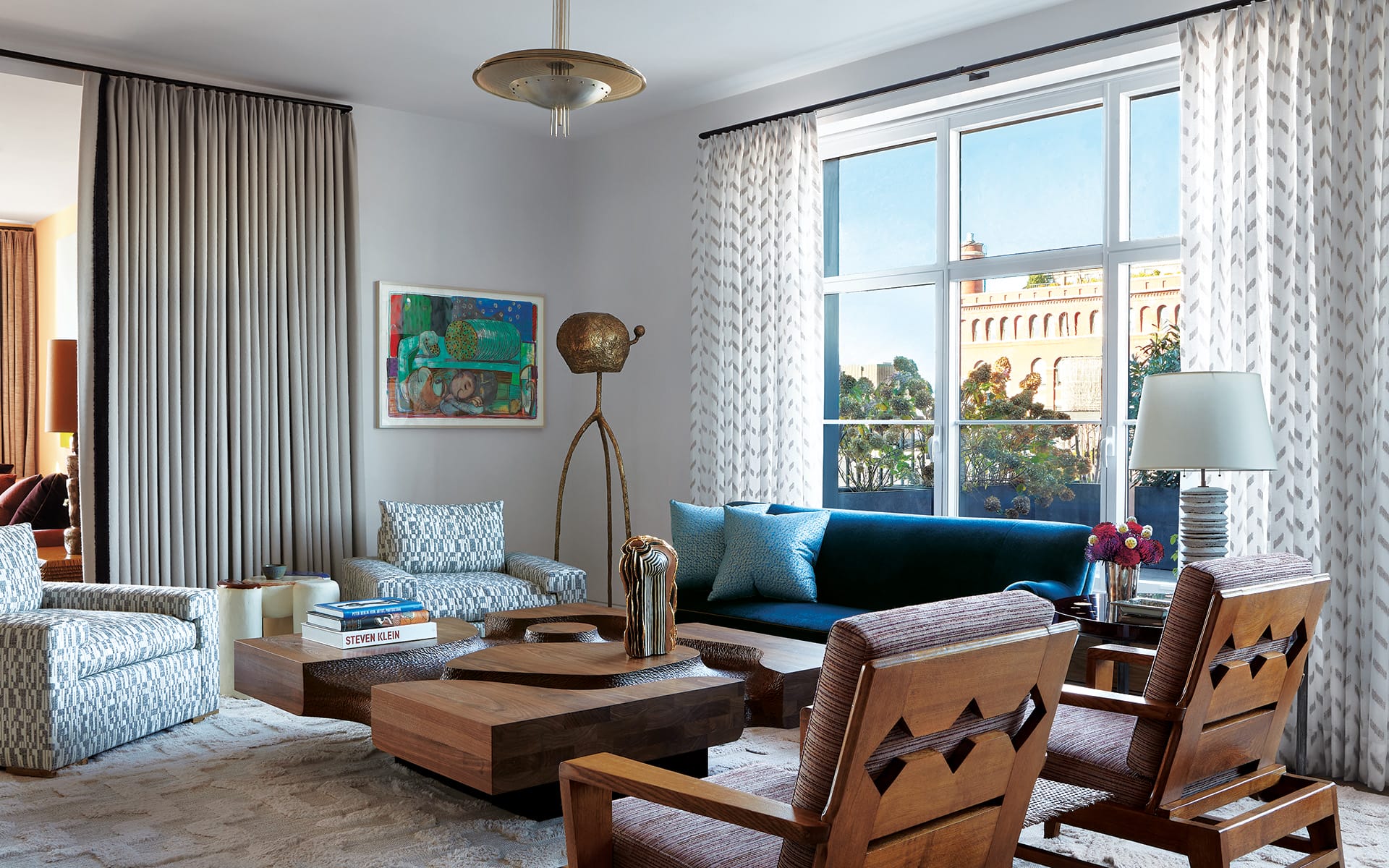 Modern living room with large windows, contemporary furniture, artwork on the wall, and decorative lamp.