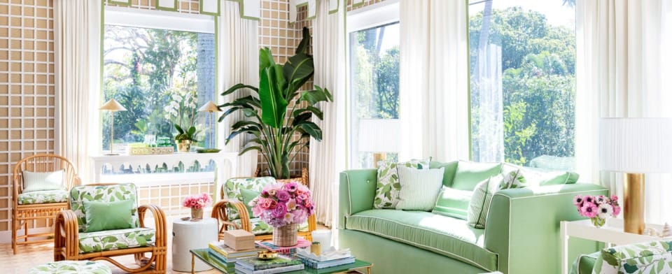 Bright, elegant living room with green and white decor, large windows, and lush plants.