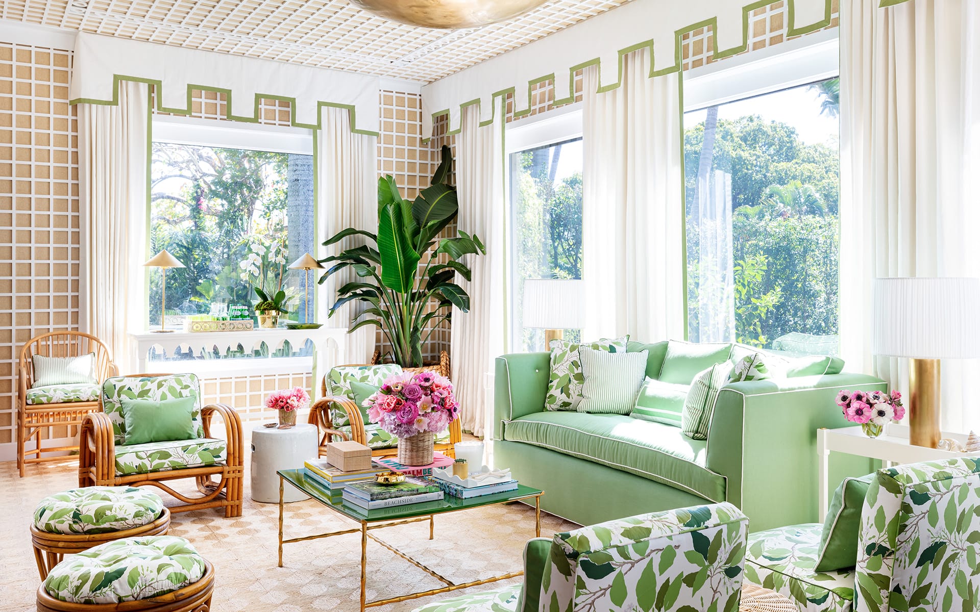 Bright, elegant living room with green and white decor, large windows, and lush plants.