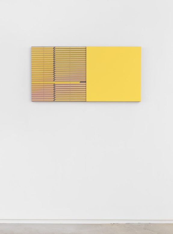 Yellow and brown abstract geometric artwork hanging on a white wall.