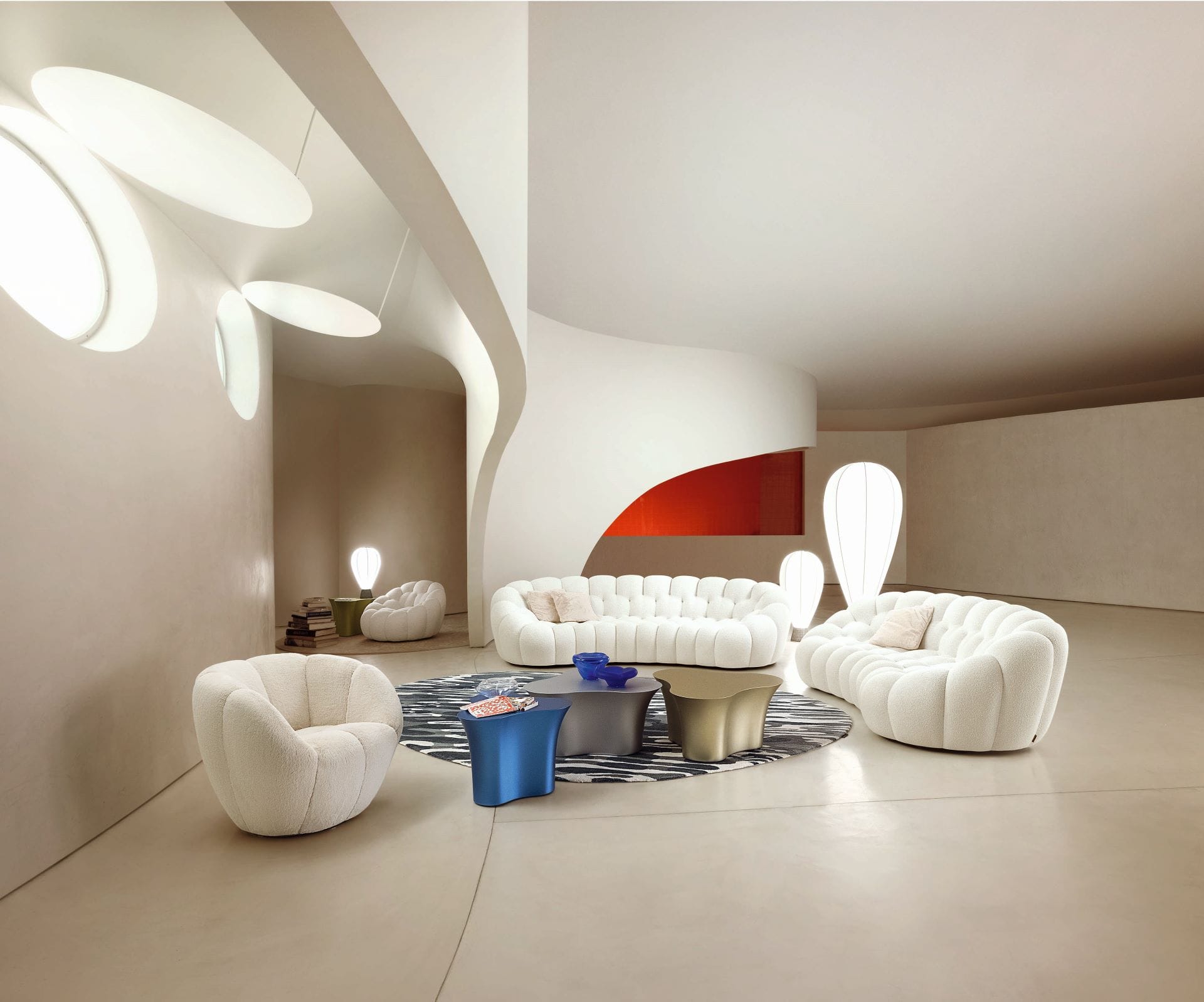 Modern living room with white tufted sofas, abstract lighting, curved walls, and a round rug with coffee tables.
