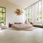 Modern bedroom with a unique tufted bed, large windows, white chair, and a feather-like chandelier.