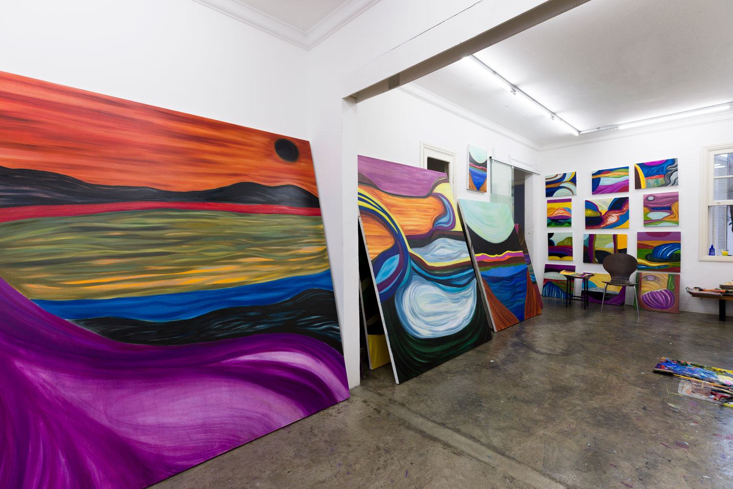 Contemporary art studio with large colorful abstract paintings displayed against white walls and on the floor.