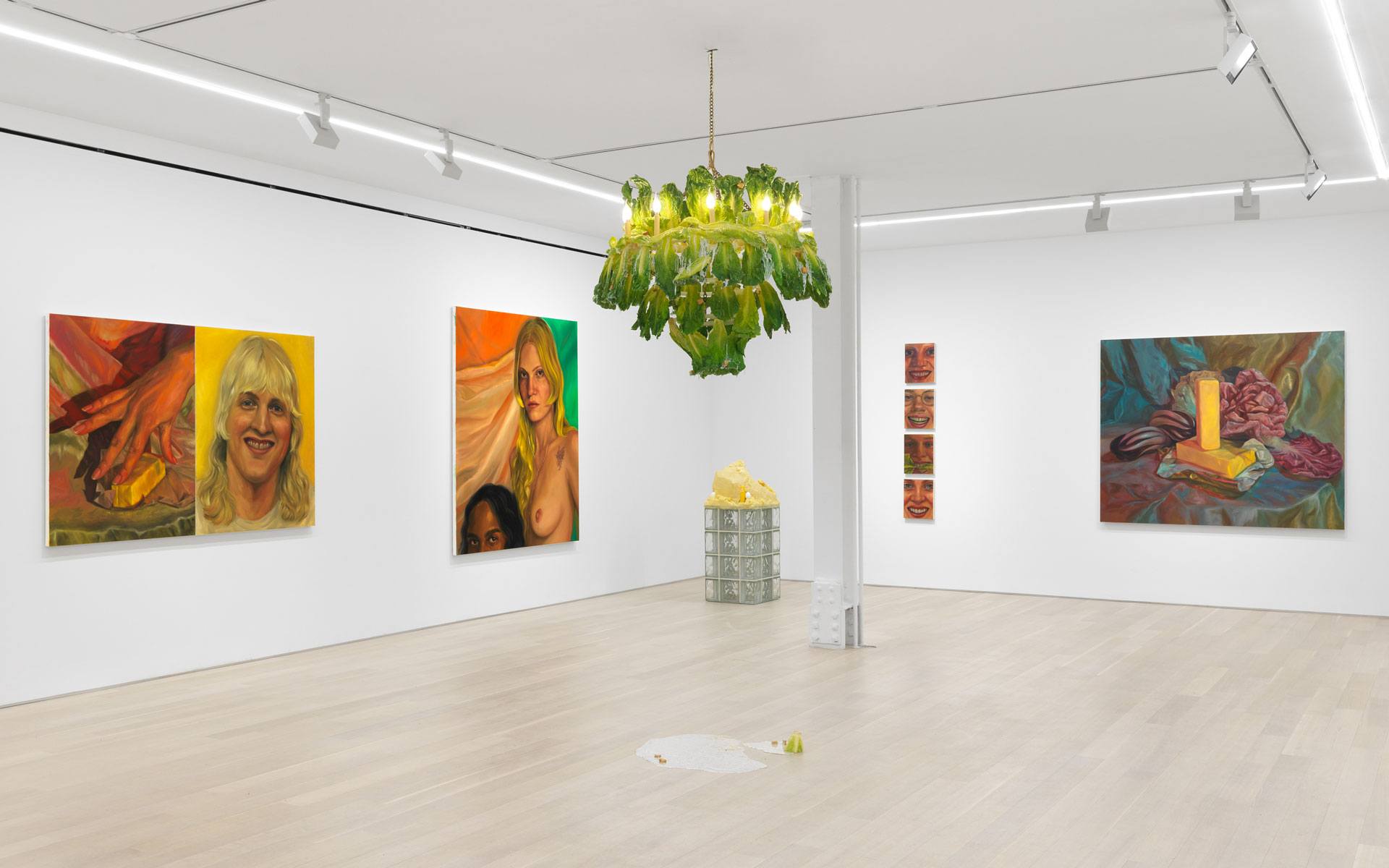 Modern art gallery with colorful paintings on white walls and a unique lettuce chandelier hanging from the ceiling.
