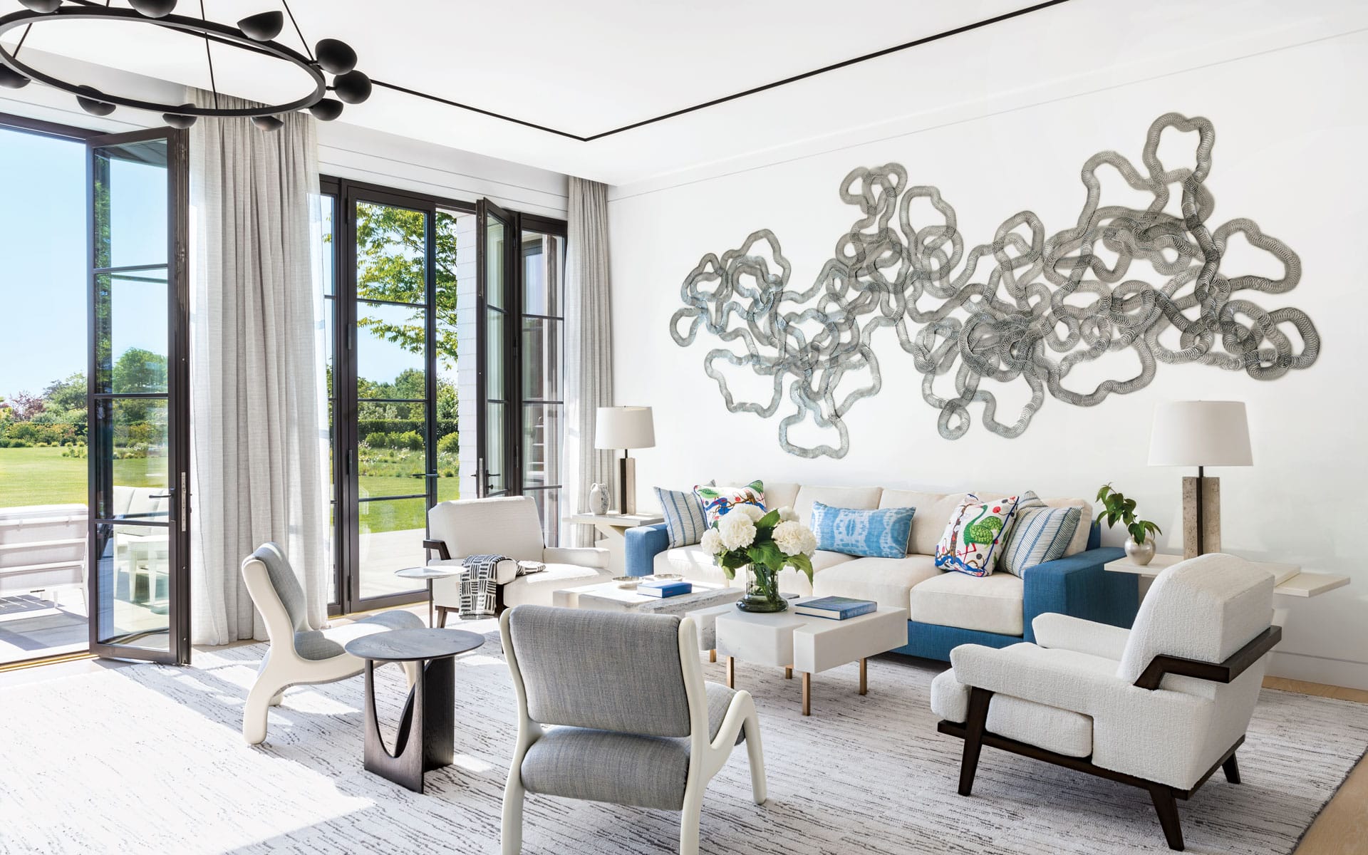 Modern living room with abstract wall art, large windows, and stylish furniture in neutral tones.
